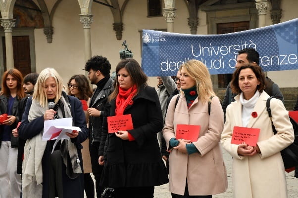 Gruppo di donne leggono ad alta voce frasi, su cartoncini rossi, contro le violenze e gli stereotipi di genere